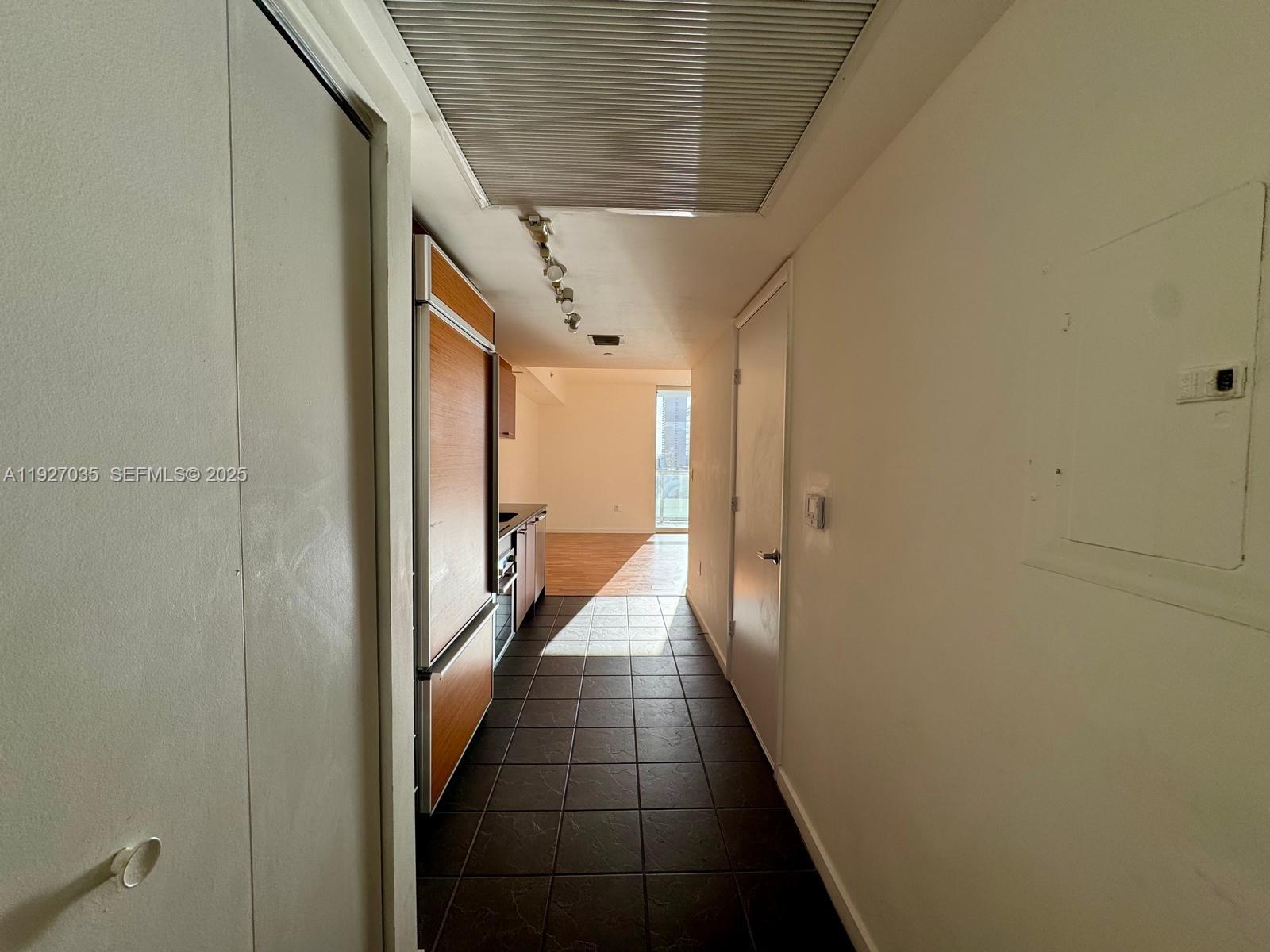 A narrow hallway with dark tile flooring leads to a kitchen and living area — 50 BISCAYNE BLVD # 1703, Miami FL 33132, MIAMI, FL
