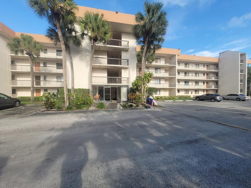A multi-story apartment building with a central entrance, balconies, and a paved parking lot — 5917 Via Vermilya # 206, Lake Worth FL 33462, LAKE WORTH, FL