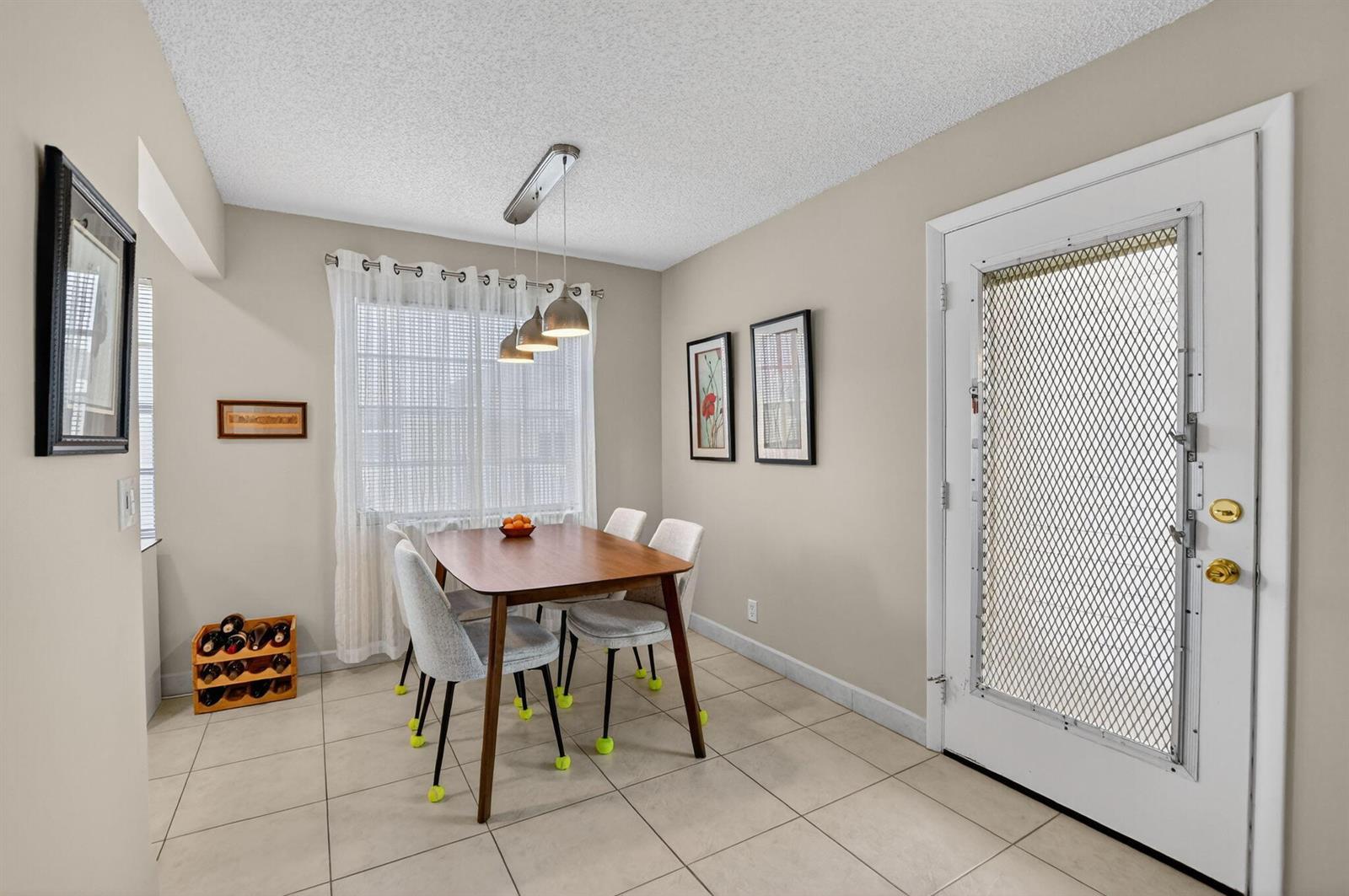 A dining area features a wooden table with tennis balls on the chair legs — 74 Burgundy B, Delray Beach FL 33484, DELRAY BEACH, FL