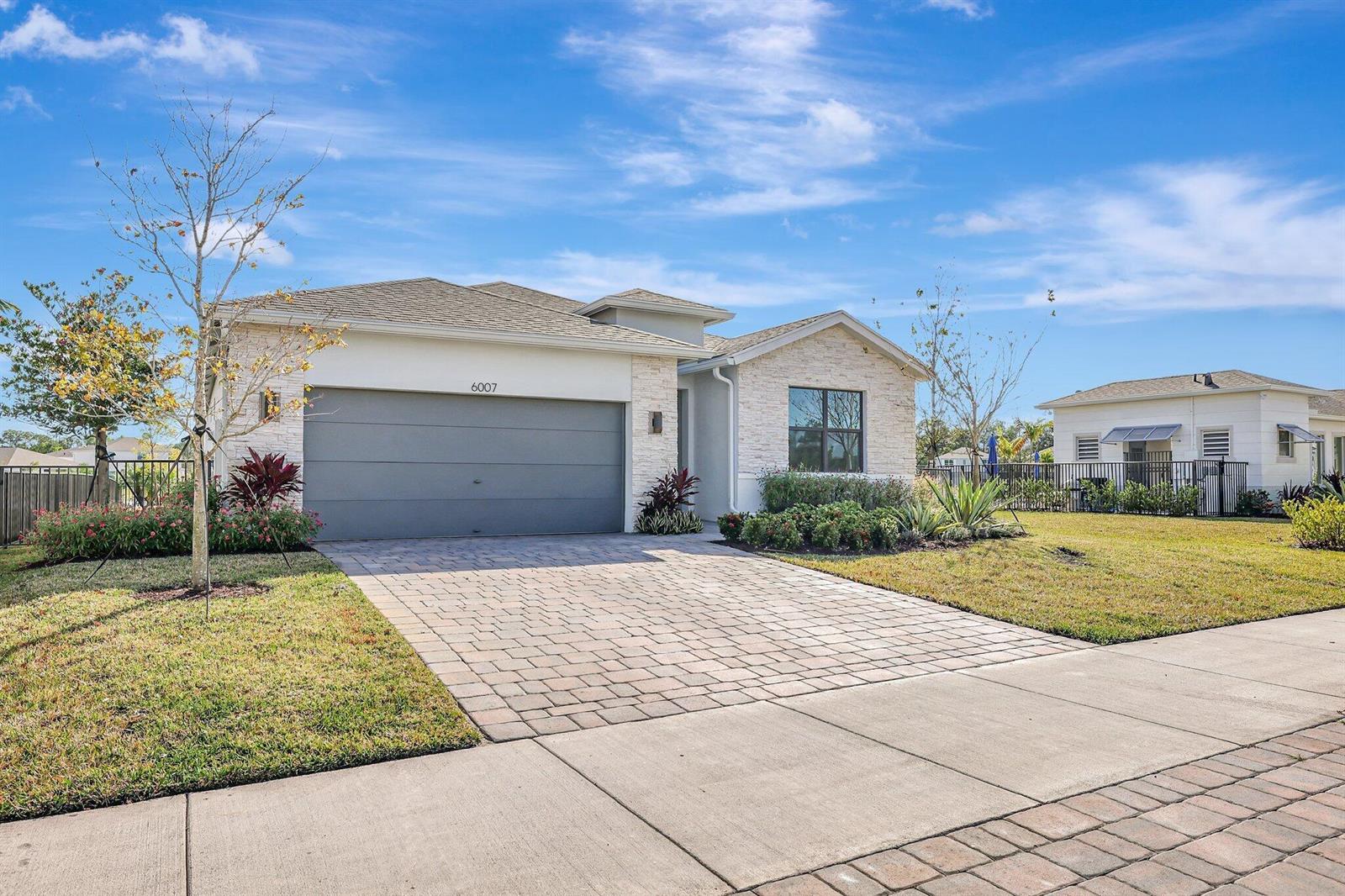 A single-story house with a stone facade, a paved driveway, and a two-car garage — 6007 SE Skyblue Circle, Stuart FL 34997, STUART, FL