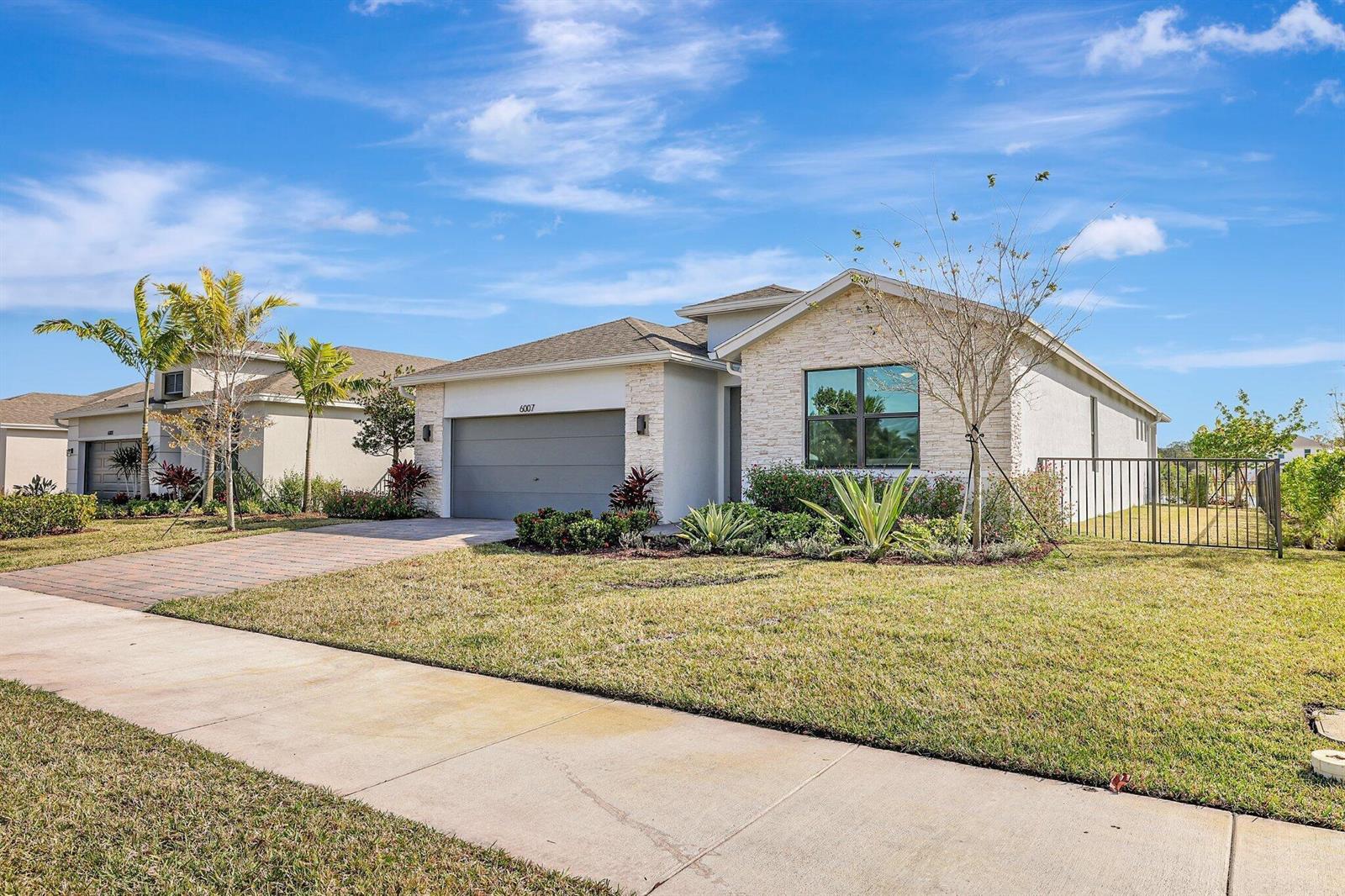 A single-story house with a stone facade, a gray garage, and a fenced side yard — 6007 SE Skyblue Circle, Stuart FL 34997, STUART, FL