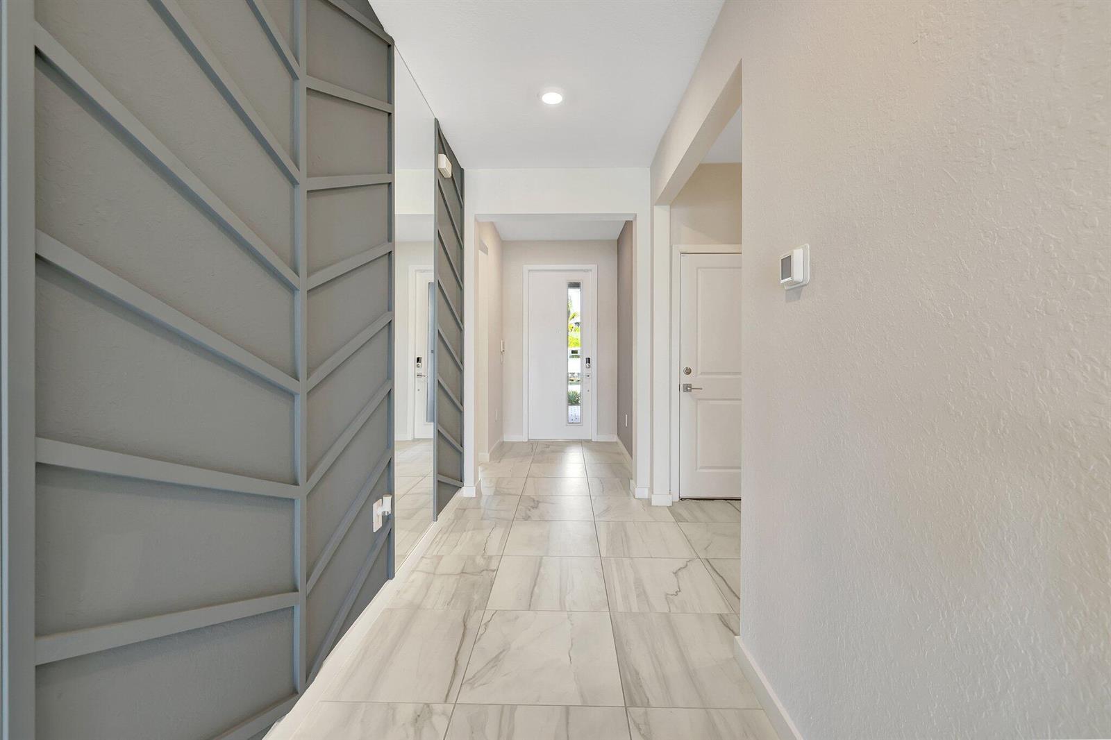 A hallway features large-format marble-look floor tiles and a gray accent wall with geometric molding — 6007 SE Skyblue Circle, Stuart FL 34997, STUART, FL