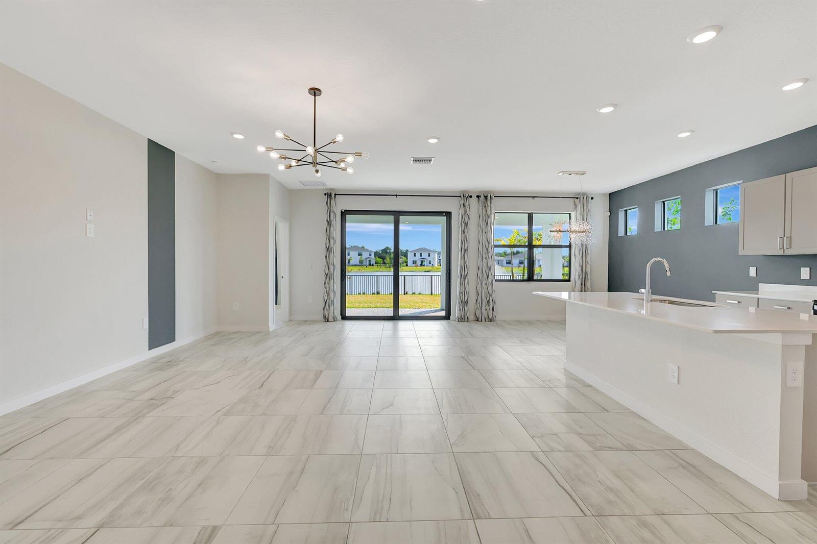 An open-concept living and kitchen area features light tile flooring and a view of water — 6007 SE Skyblue Circle, Stuart FL 34997, STUART, FL