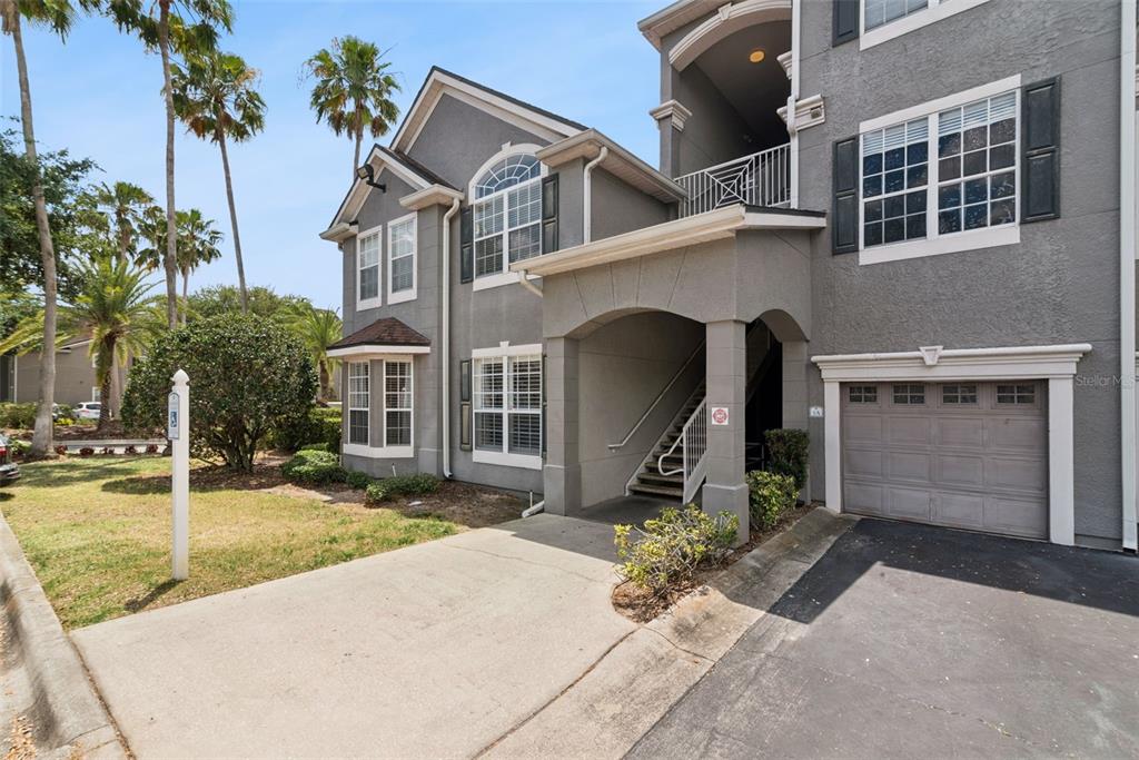 A two-story gray stucco townhouse with a single-car garage and an exterior staircase — 3307 S KIRKMAN ROAD UNIT 110, ORLANDO, FL