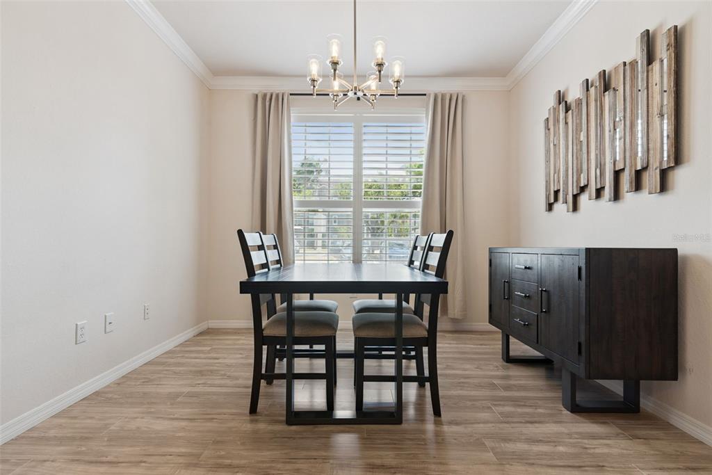 A dining room features a dark wood table, four chairs, a sideboard, and a chandelier — 3307 S KIRKMAN ROAD UNIT 110, ORLANDO, FL