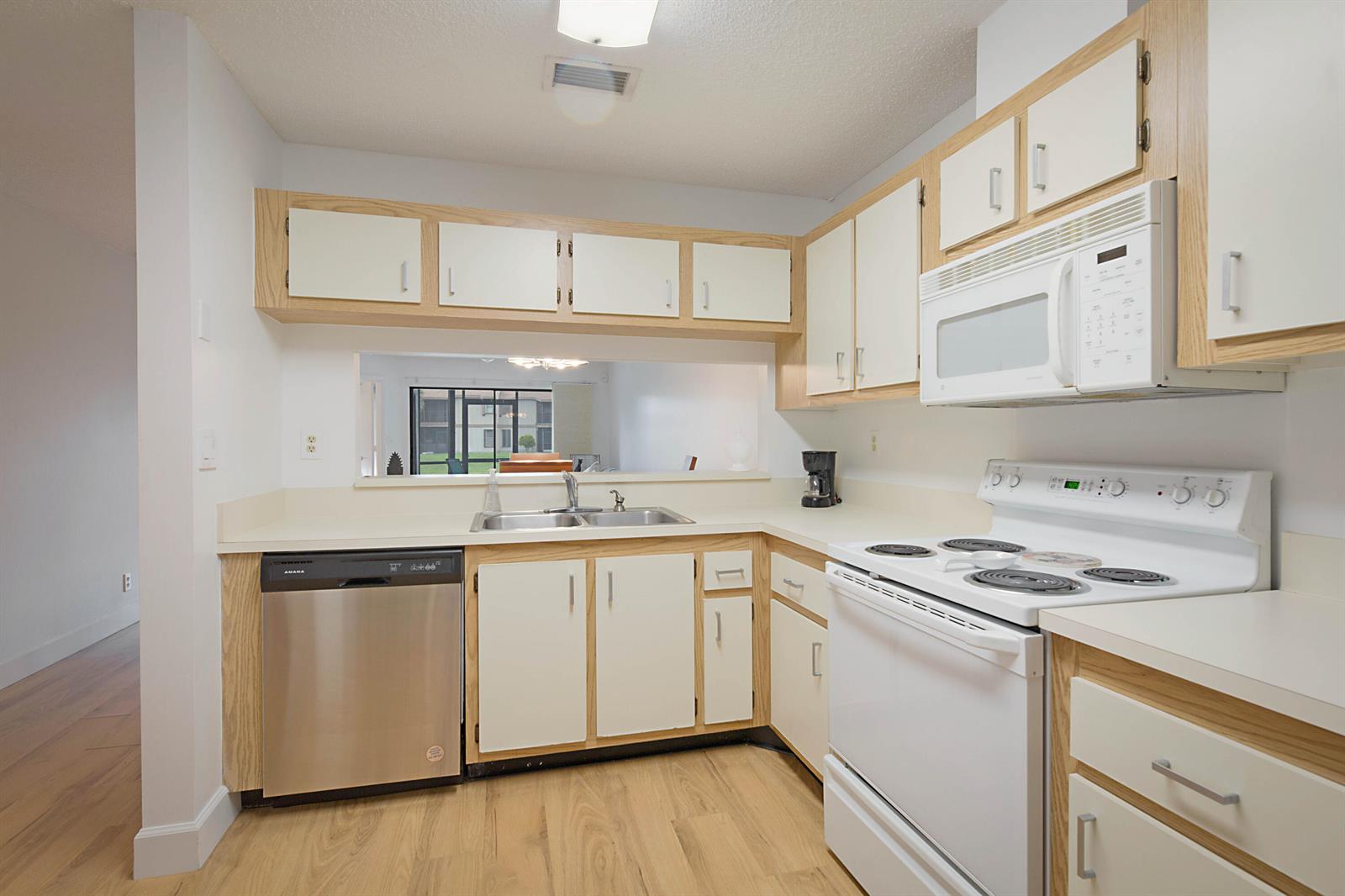 A kitchen with white cabinets, oak trim, stainless steel dishwasher, and white appliances — 903 Harbour Pointe Way, FL 33413, FL