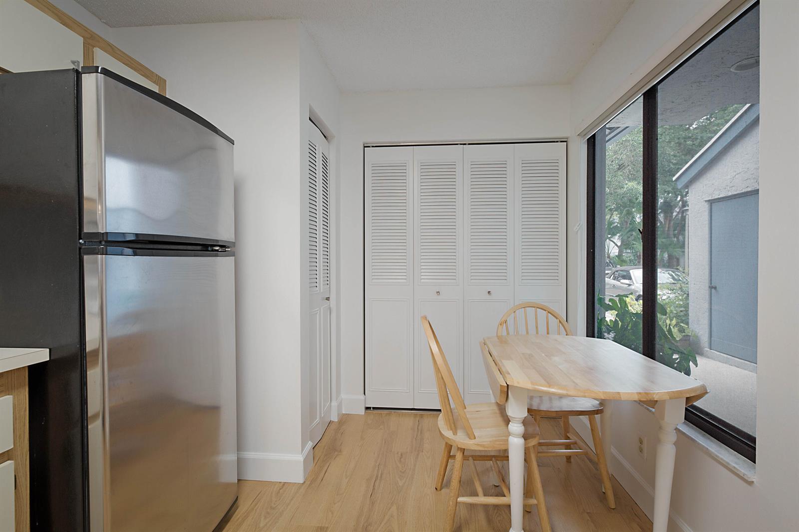 A kitchen dining area features a stainless steel refrigerator, light wood flooring, and a window — 903 Harbour Pointe Way, FL 33413, FL