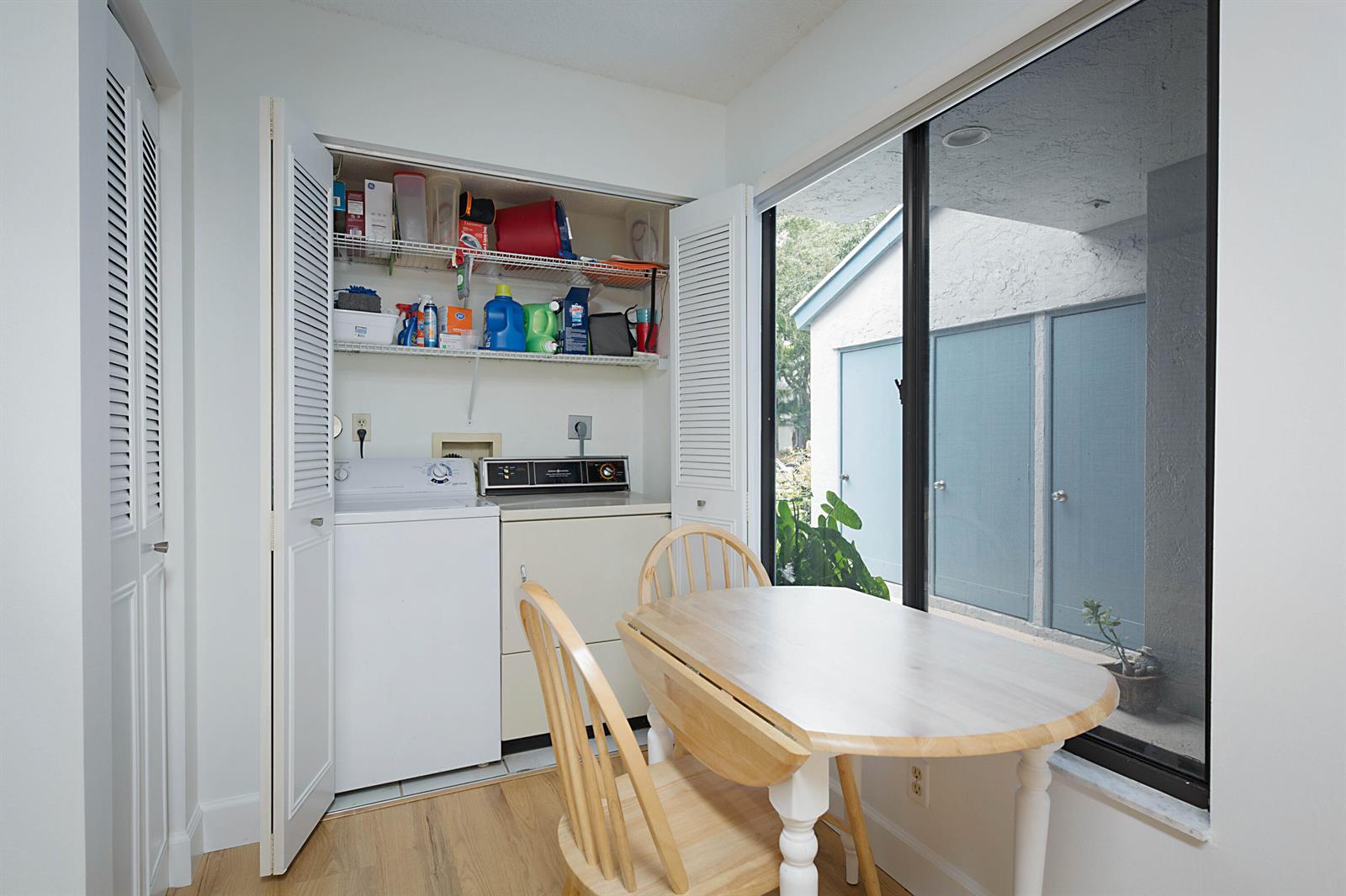 A laundry closet with a washer and dryer sits next to a dining table indoors — 903 Harbour Pointe Way, FL 33413, FL