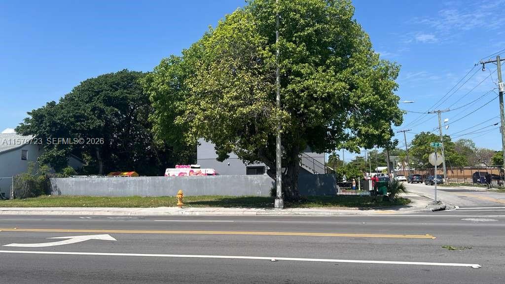 A large tree stands in front of a gray building on a street corner — 6928 NW 17th Ave, Miami FL 33147, MIAMI, FL