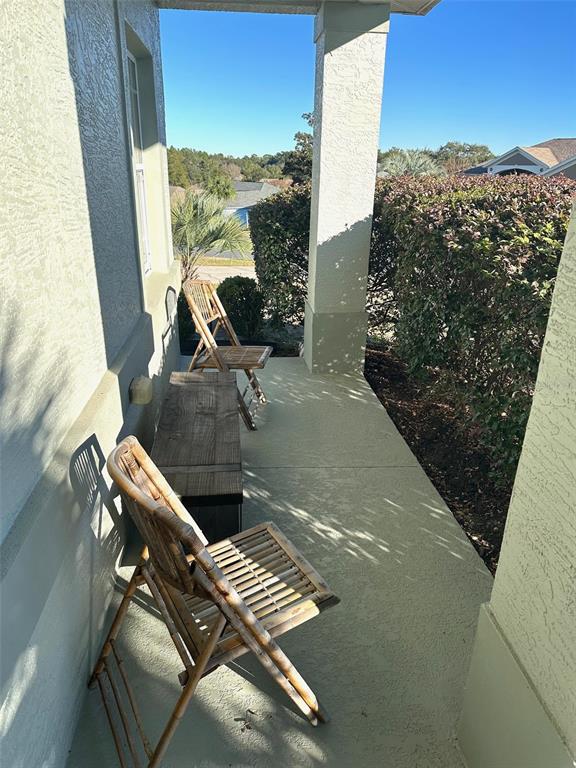 A covered porch features two bamboo chairs and a wooden bench on a concrete floor — 251 W REXFORD DRIVE, BEVERLY HILLS, FL