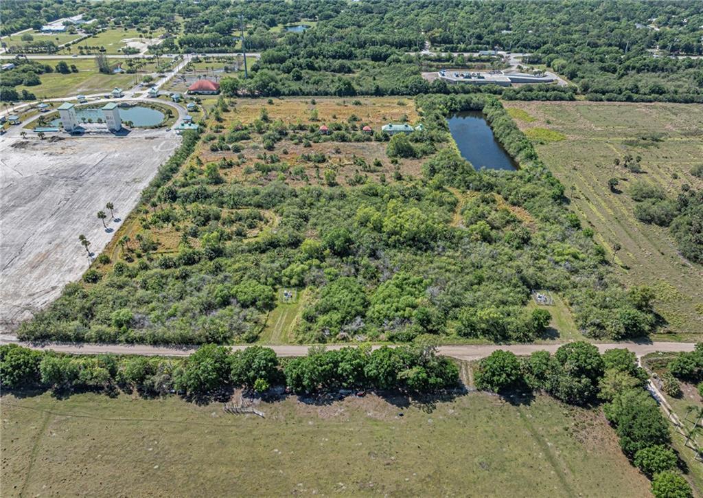 An aerial view shows a large, undeveloped plot of land with trees and a pond — 9555 Mesa Park C Boulevard, Fellsmere FL 32948, FELLSMERE, FL