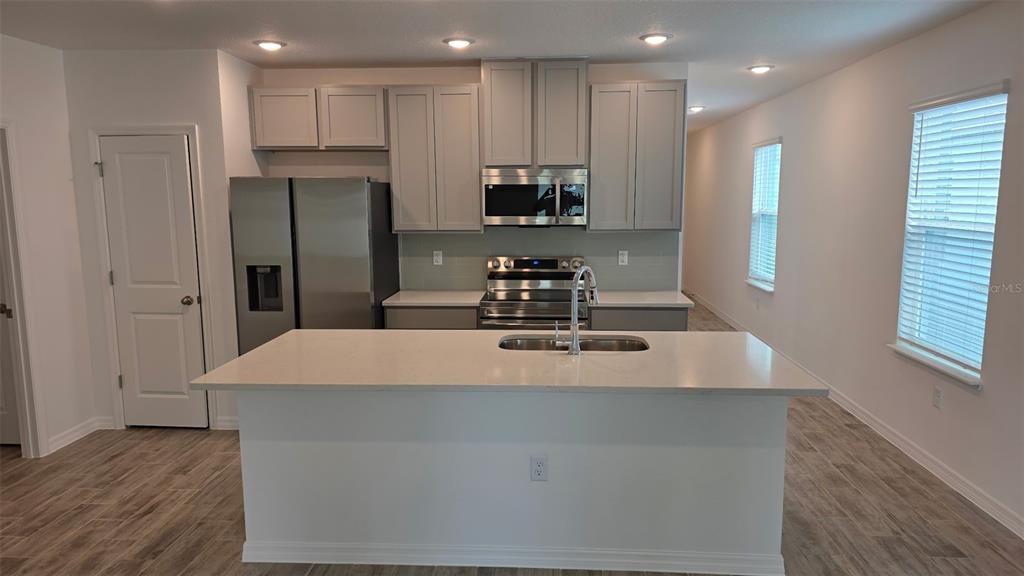 A modern kitchen features a large island, stainless steel appliances, and light gray cabinetry — 5535 MADDIE DRIVE, HAINES CITY, FL