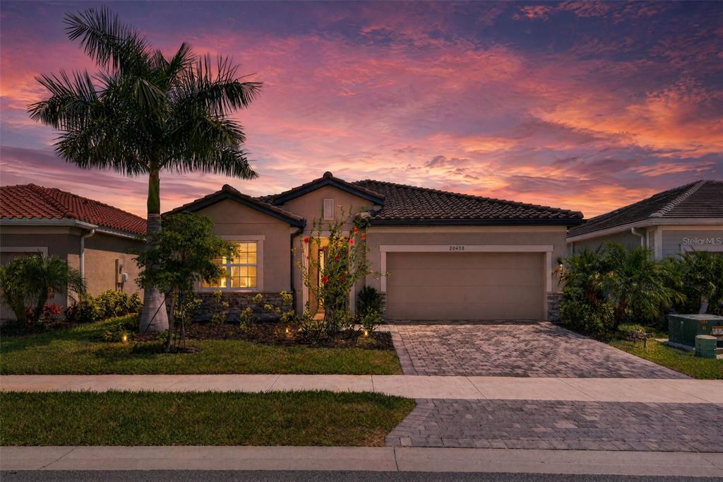 A single-story house with a paved driveway and a palm tree under a sunset sky — 20458 BANDERA PLACE, VENICE, FL