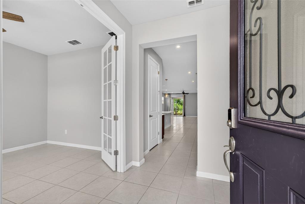 A view from an open front door into a tiled entryway with French doors — 20458 BANDERA PLACE, VENICE, FL