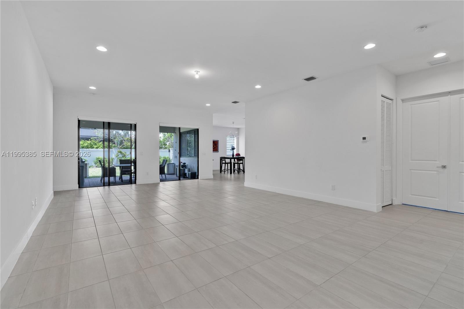 A spacious, white-walled living area features light-colored tile flooring and sliding glass patio doors — 4528 SW 178th Ave, Miramar FL 33029, MIRAMAR, FL