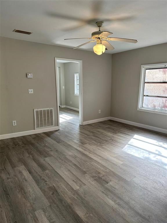 A room with light gray walls, wood-look flooring, a ceiling fan, and a doorway leading elsewhere — 1219 W 8TH STREET, SANFORD, FL
