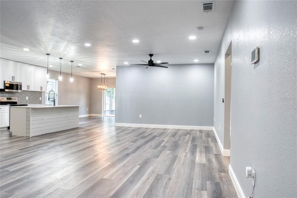 An open-concept kitchen and living area featuring white cabinetry, a kitchen island, and wood-look flooring — 3711 JULIUS ESTATES BOULEVARD, WINTER HAVEN, FL