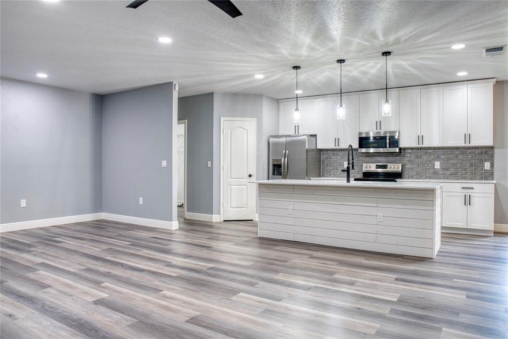 A kitchen with white cabinets, a shiplap island, and gray wood-look flooring — 3711 JULIUS ESTATES BOULEVARD, WINTER HAVEN, FL