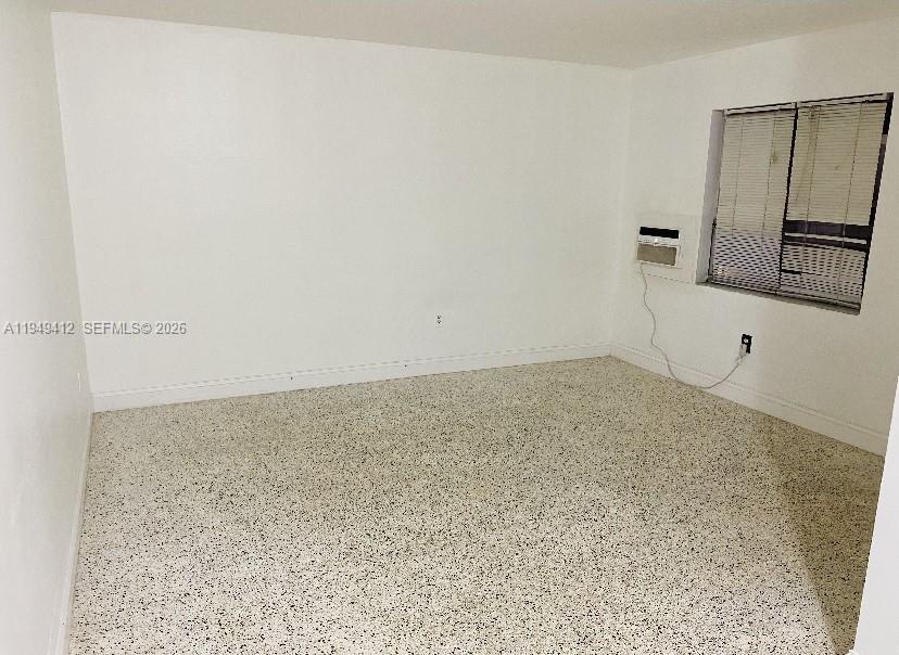 An empty room features white walls, a window with blinds, and speckled terrazzo flooring — 626 NE 61st St # 5, Miami FL 33137, MIAMI, FL