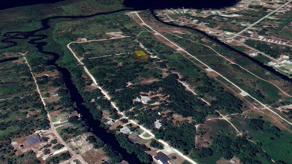 An aerial view shows a vacant, rectangular lot highlighted in yellow amidst a wooded landscape — 1461 PALSGRAVE DRIVE, PUNTA GORDA, FL