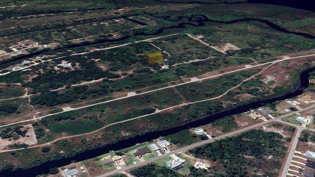 An aerial view shows a vacant lot highlighted in yellow within a rural, undeveloped landscape — 1461 PALSGRAVE DRIVE, PUNTA GORDA, FL