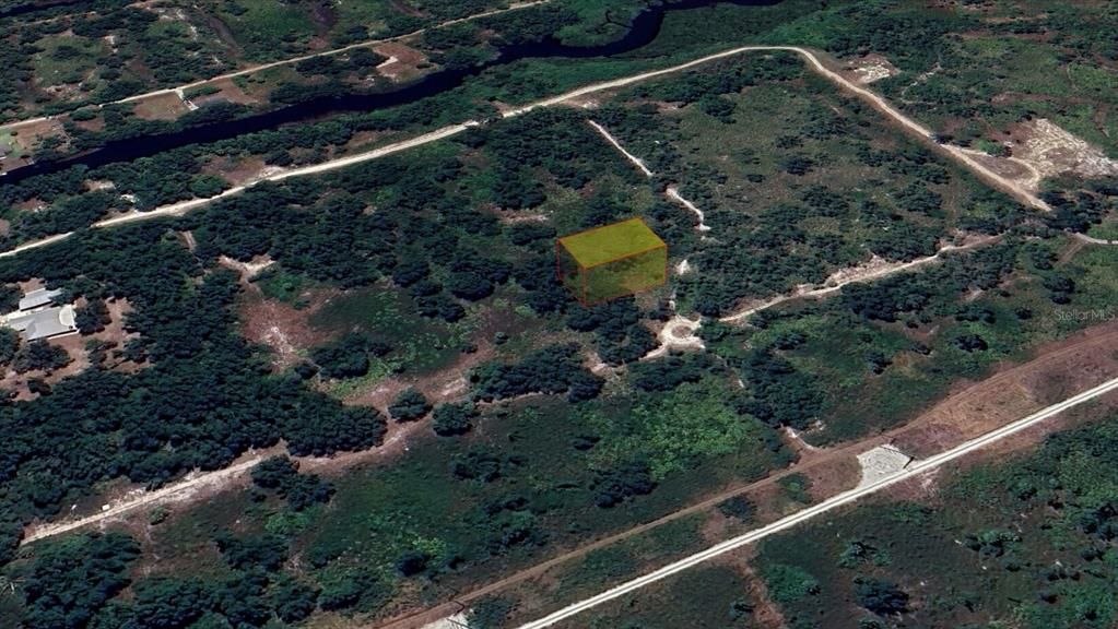 An aerial view shows a rectangular plot of land highlighted in yellow amidst undeveloped terrain — 1461 PALSGRAVE DRIVE, PUNTA GORDA, FL