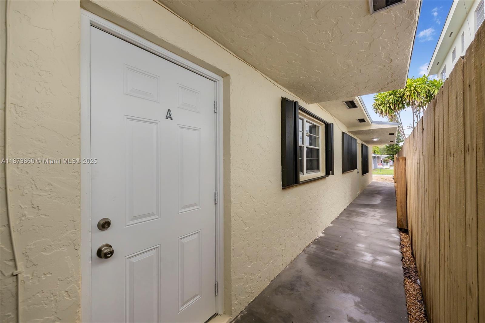 A white door marked with an A leads to a concrete walkway beside a fence — 2033 Dewey St, Hollywood FL 33020, HOLLYWOOD, FL