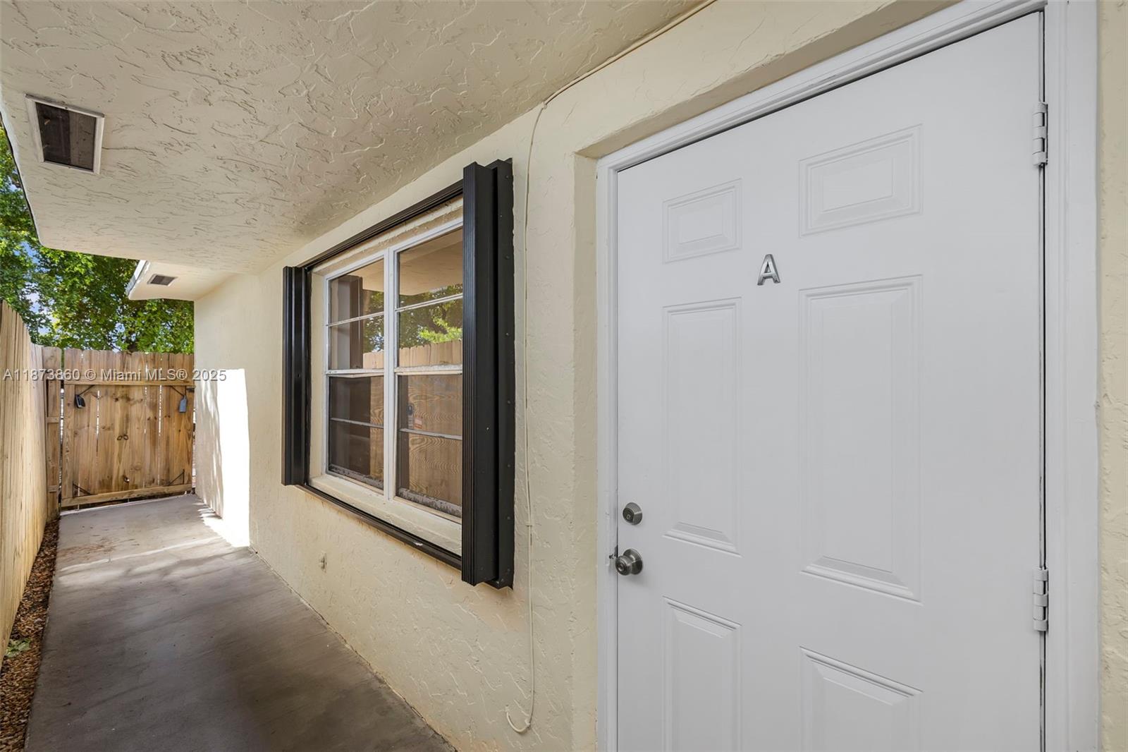 A white door labeled A sits beside a window on a covered concrete patio — 2033 Dewey St, Hollywood FL 33020, HOLLYWOOD, FL