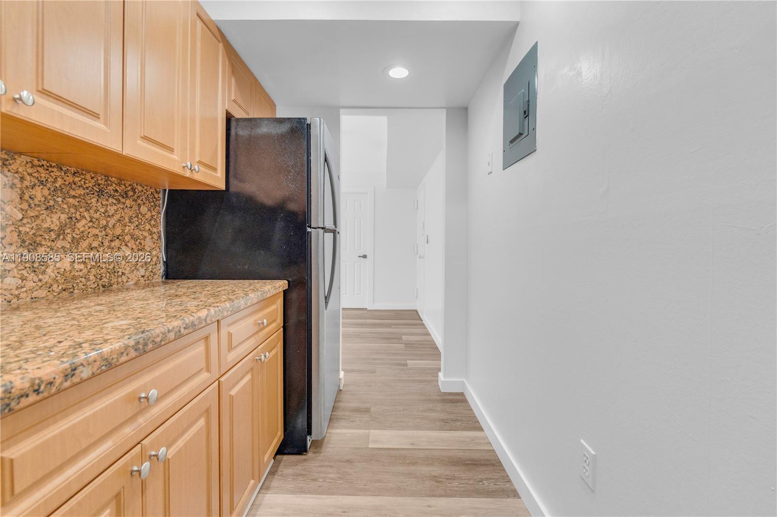 A kitchen features light wood cabinets, granite countertops, a black refrigerator, and wood-look flooring — 4709 NW 7th St # 9, Miami FL 33126, MIAMI, FL