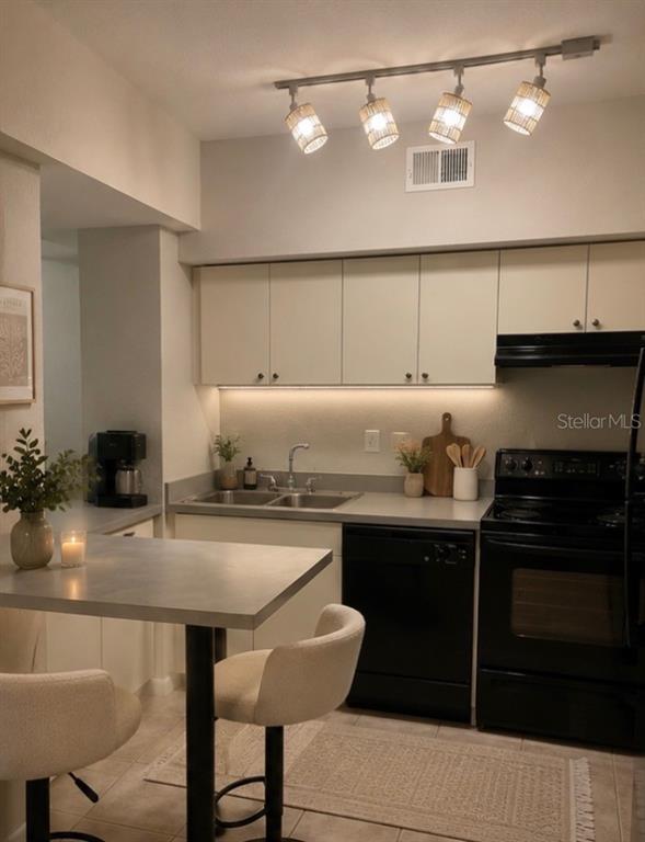 A kitchen features light-colored cabinets, a gray countertop, black appliances, and a small dining table — 2411 W HORATIO STREET UNIT 538, TAMPA, FL