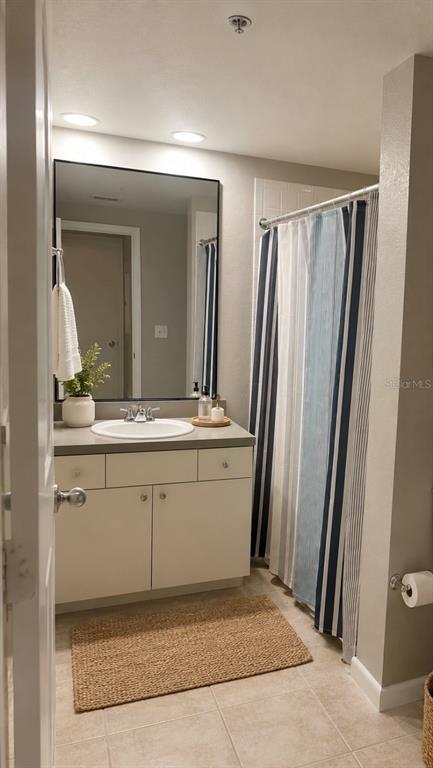 A bathroom features a white vanity, a large rectangular mirror, and a striped shower curtain — 2411 W HORATIO STREET UNIT 538, TAMPA, FL