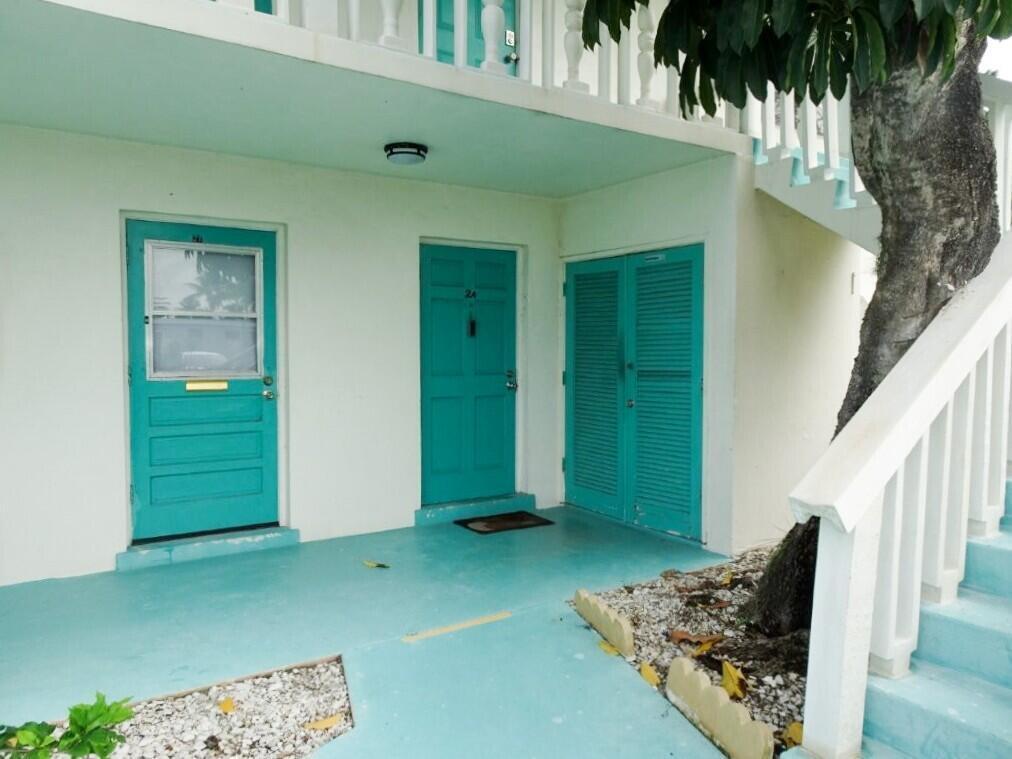 A white building exterior features two turquoise doors, a louvered closet, and a staircase — 213 SE 3rd Avenue # 2a, Boynton Beach FL 33435, BOYNTON BEACH, FL
