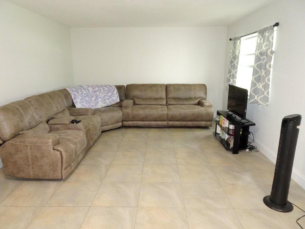 A living room featuring a large brown sectional sofa, tile flooring, and a television stand — 213 SE 3rd Avenue # 2a, Boynton Beach FL 33435, BOYNTON BEACH, FL