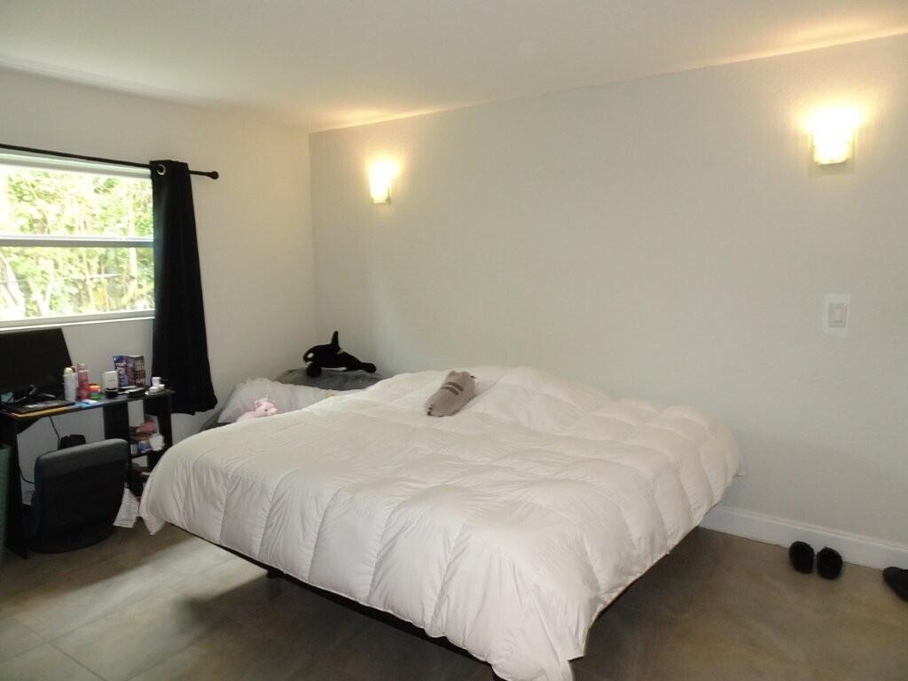 A bedroom features a large bed with a white comforter, wall sconces, and a desk area — 213 SE 3rd Avenue # 2a, Boynton Beach FL 33435, BOYNTON BEACH, FL