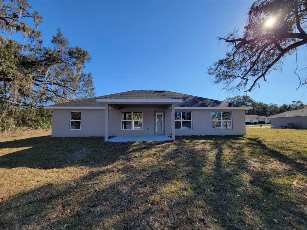 The rear exterior of a single-story house features a covered patio and a grassy yard — 14578 SW 69TH COURT ROAD, OCALA, FL
