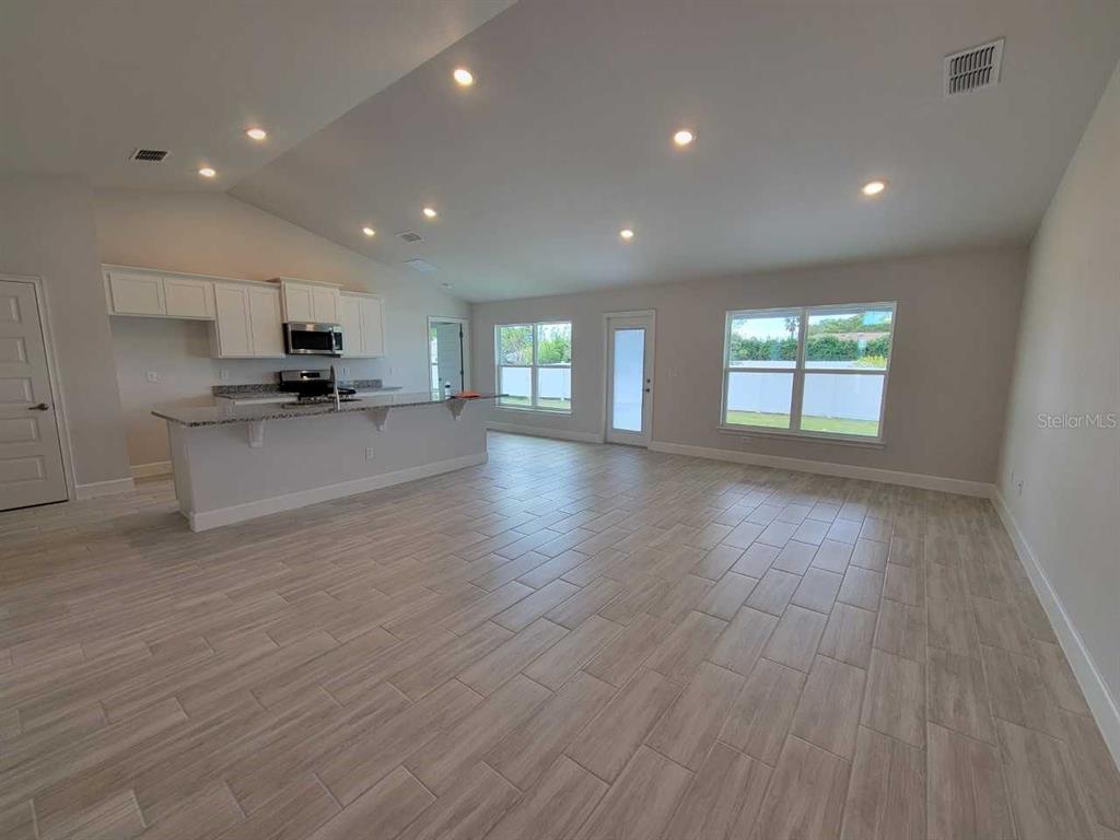 An open-concept kitchen and living area featuring light wood-look tile flooring and white cabinetry — 14578 SW 69TH COURT ROAD, OCALA, FL