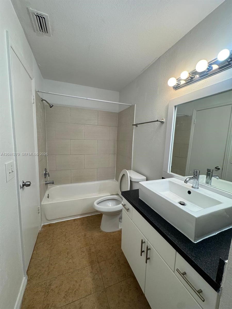 A bathroom features a white vanity with a vessel sink, a toilet, and a tiled tub — 3400 N Pinewalk Dr N # 924, Margate FL 33063, MARGATE, FL