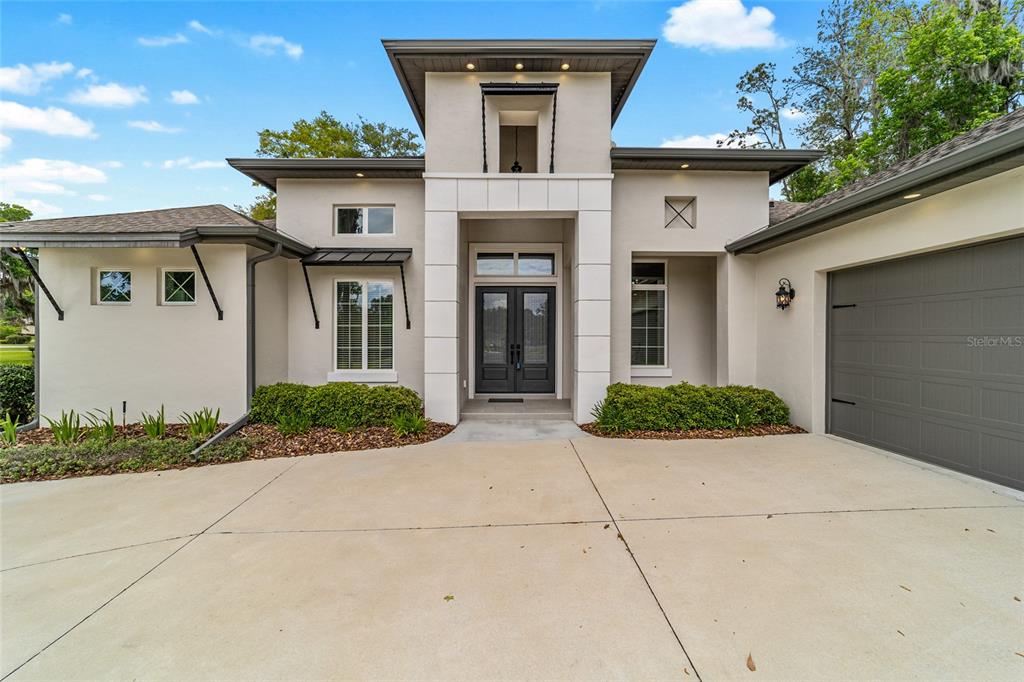 The exterior of a modern house features a concrete driveway, double front doors, and garage — 1003 SE 46TH STREET, OCALA, FL