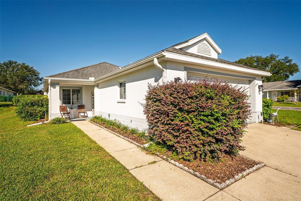 A single-story house exterior features a concrete driveway, a front walkway, and a large bush — 2048 NW 50TH AVENUE, OCALA, FL