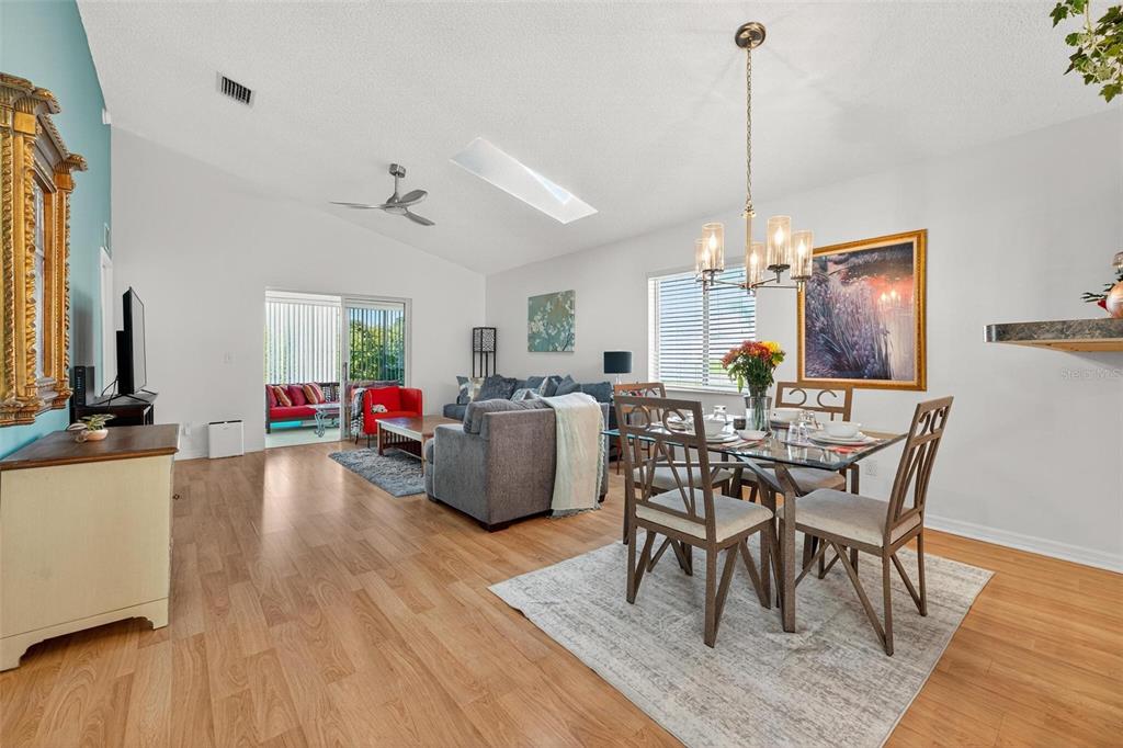 A living and dining area with wood-look flooring, vaulted ceilings, and a glass dining table — 2048 NW 50TH AVENUE, OCALA, FL