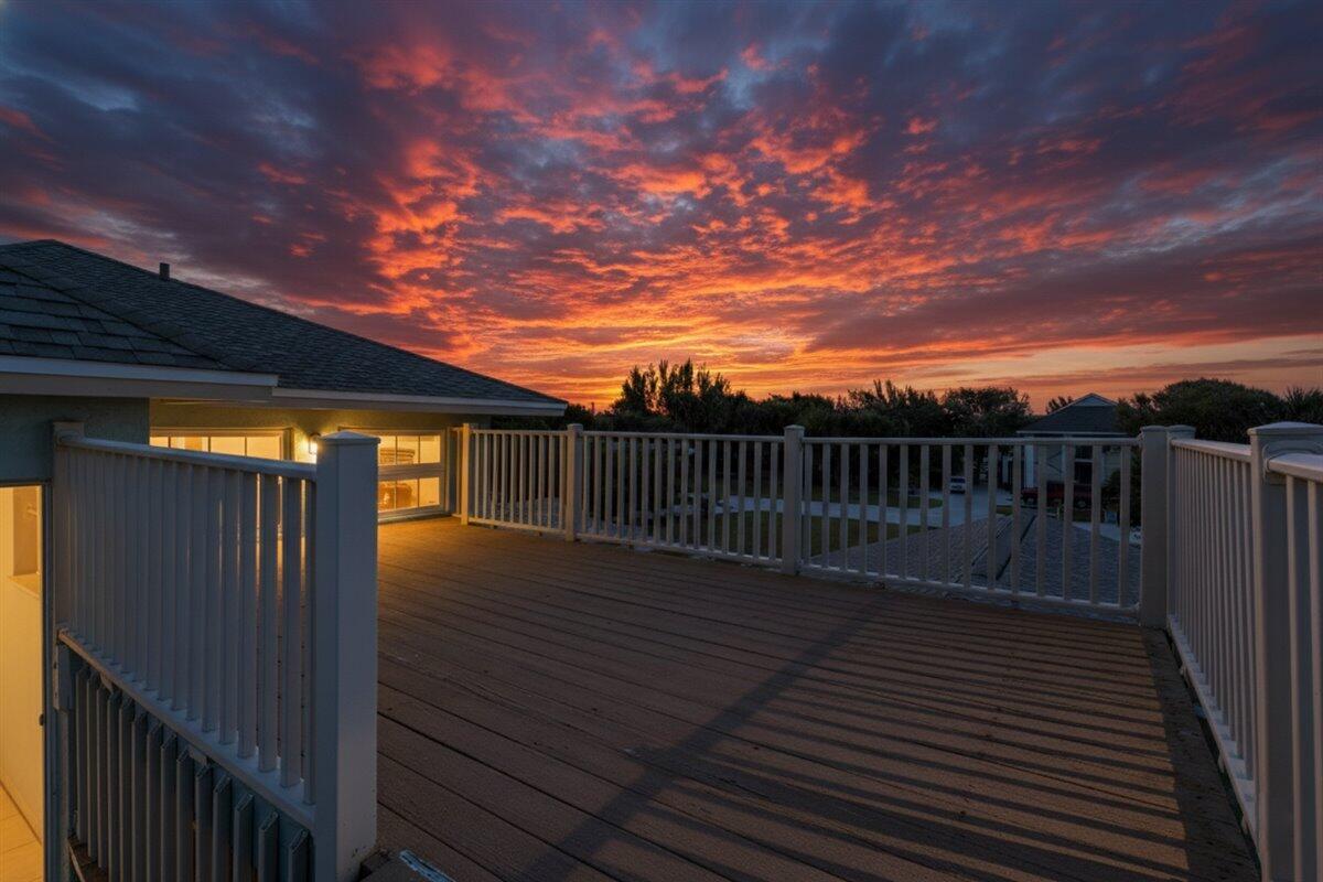A wooden deck with white railings overlooks a house under a vibrant sunset sky — 2309 Atlantic Beach Boulevard, Fort Pierce FL 34949, FORT PIERCE, FL