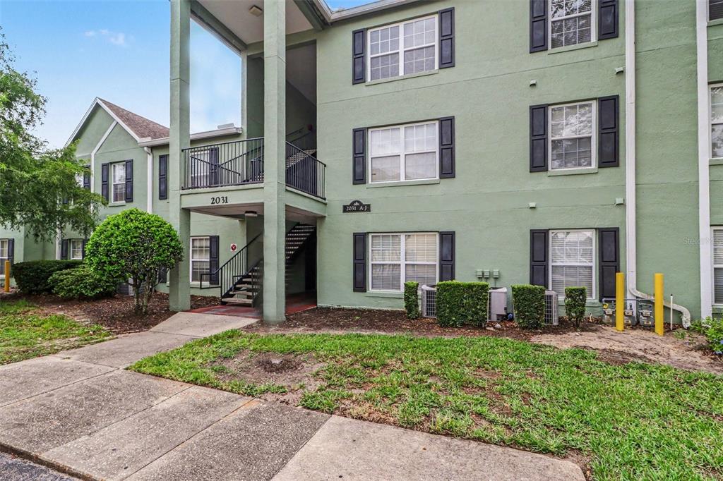 A three-story apartment building with green stucco siding, black shutters, and an outdoor staircase — 2031 DIXIE BELLE DRIVE UNIT 2031C, ORLANDO, FL