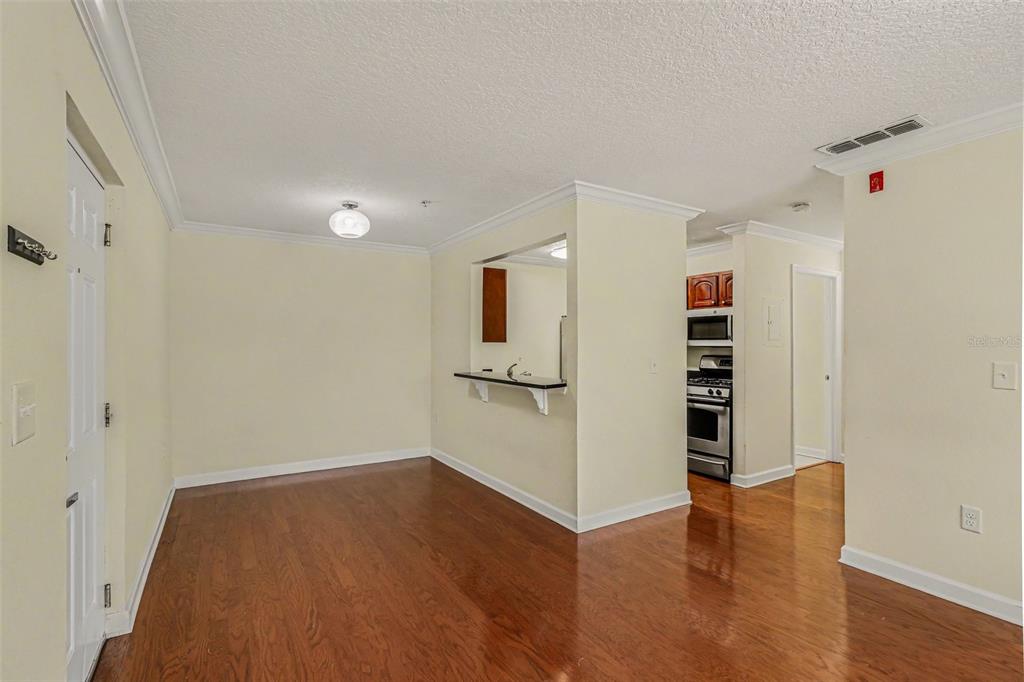 An interior view shows a dining area with hardwood floors, a pass-through window, and kitchen — 2031 DIXIE BELLE DRIVE UNIT 2031C, ORLANDO, FL