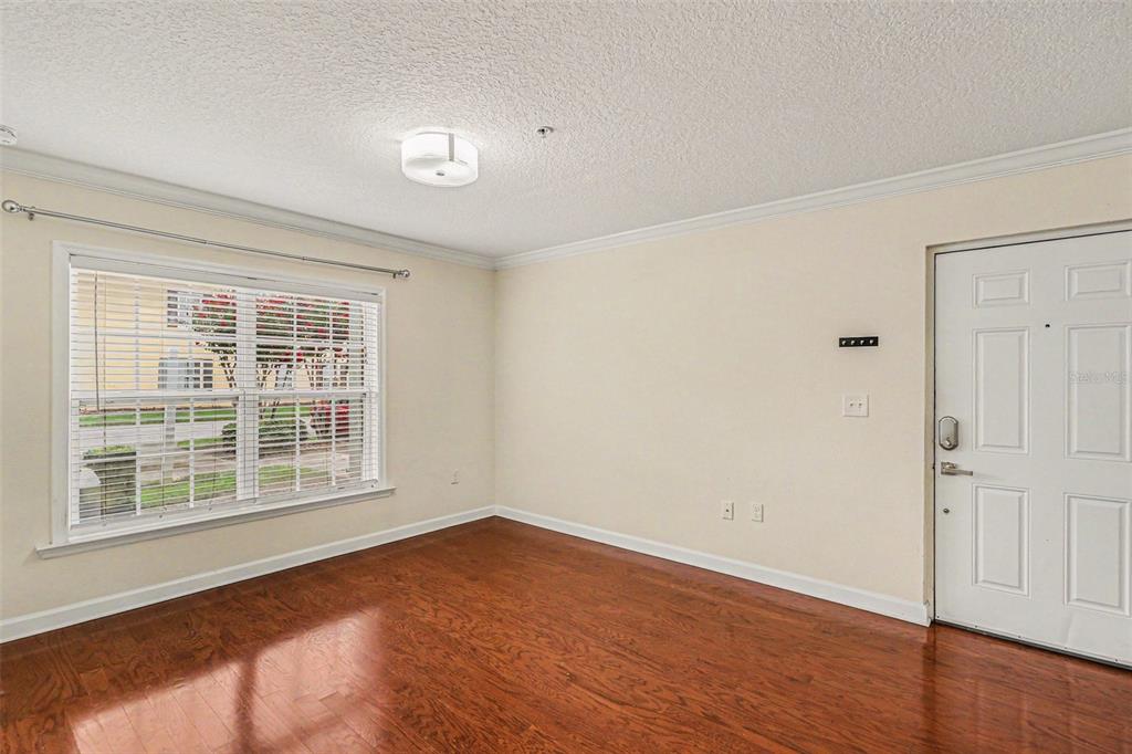 An empty room with hardwood floors, a large window, and a white entry door — 2031 DIXIE BELLE DRIVE UNIT 2031C, ORLANDO, FL