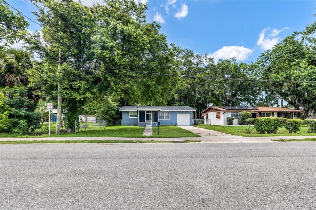 A blue single-story house with a white garage and a front yard with trees — 906 MAGNOLIA AVENUE, DAYTONA BEACH, FL