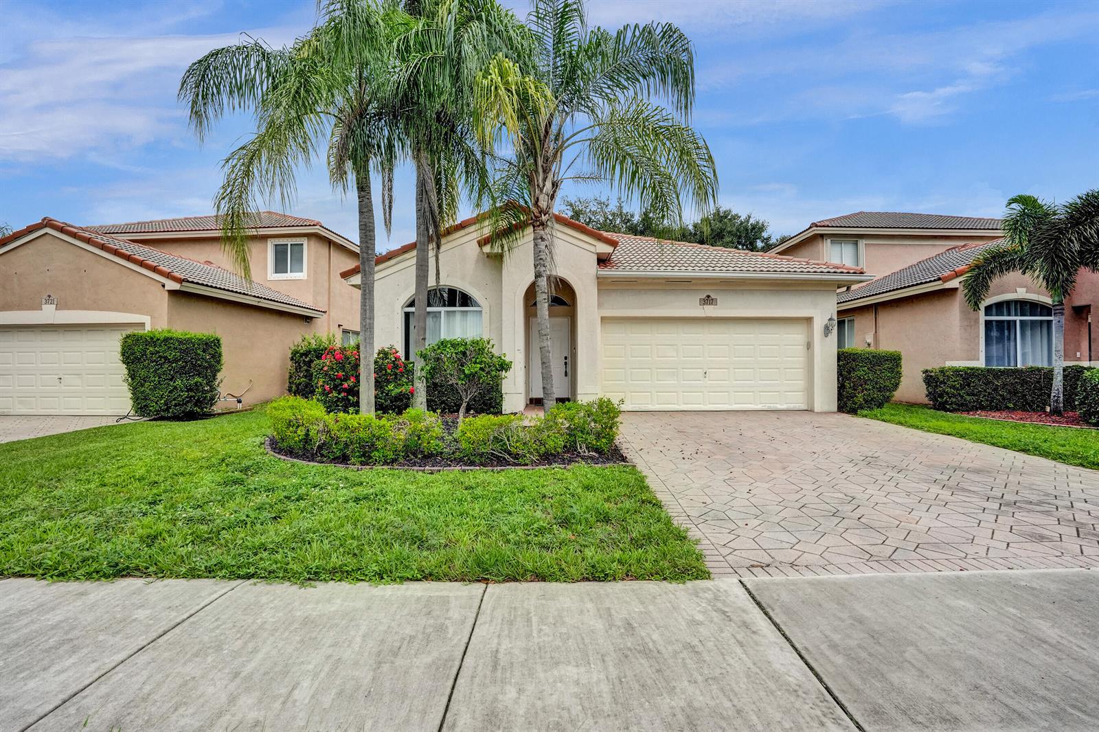 The exterior of a single-story suburban house features a paved driveway, palm trees, and landscaping — 3717 Pebblebrook Manor, Coconut Creek FL 33073, COCONUT CREEK, FL