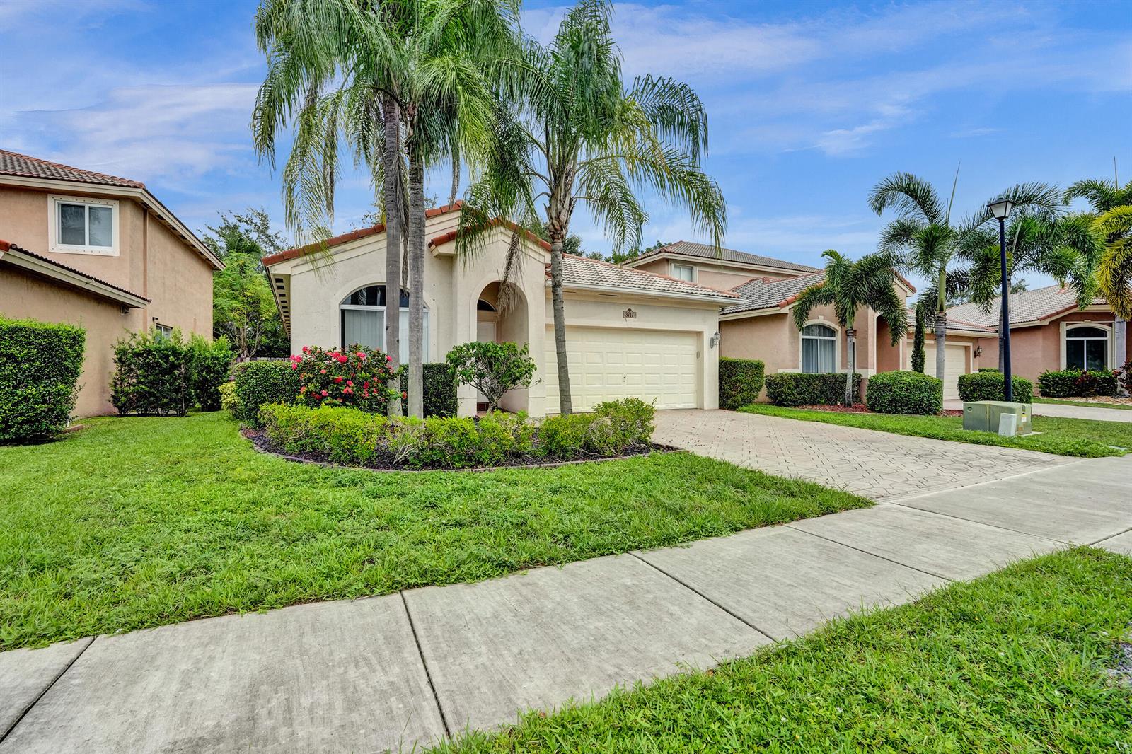 A single-story suburban house with a two-car garage, palm trees, and a paved driveway — 3717 Pebblebrook Manor, Coconut Creek FL 33073, COCONUT CREEK, FL