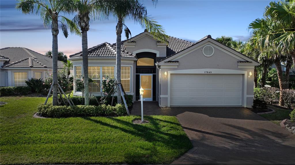 A single-story house with a two-car garage, tile roof, and palm trees in the front yard — 17849 HIBISCUS COVE COURT UNIT 1, PUNTA GORDA, FL