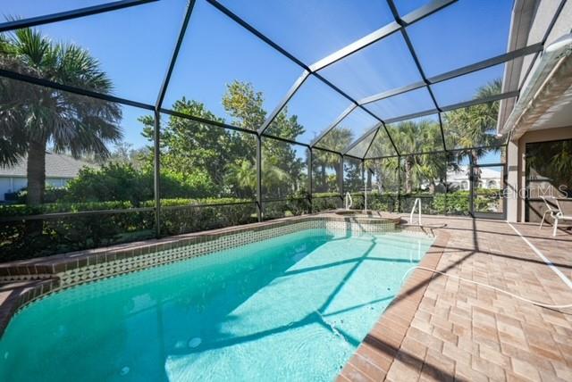 A screened-in swimming pool and spa are surrounded by a brick paver patio — 17849 HIBISCUS COVE COURT UNIT 1, PUNTA GORDA, FL