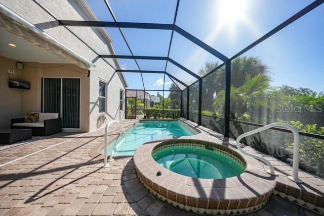 A screened-in patio features a swimming pool, a raised hot tub, and outdoor seating — 17849 HIBISCUS COVE COURT UNIT 1, PUNTA GORDA, FL